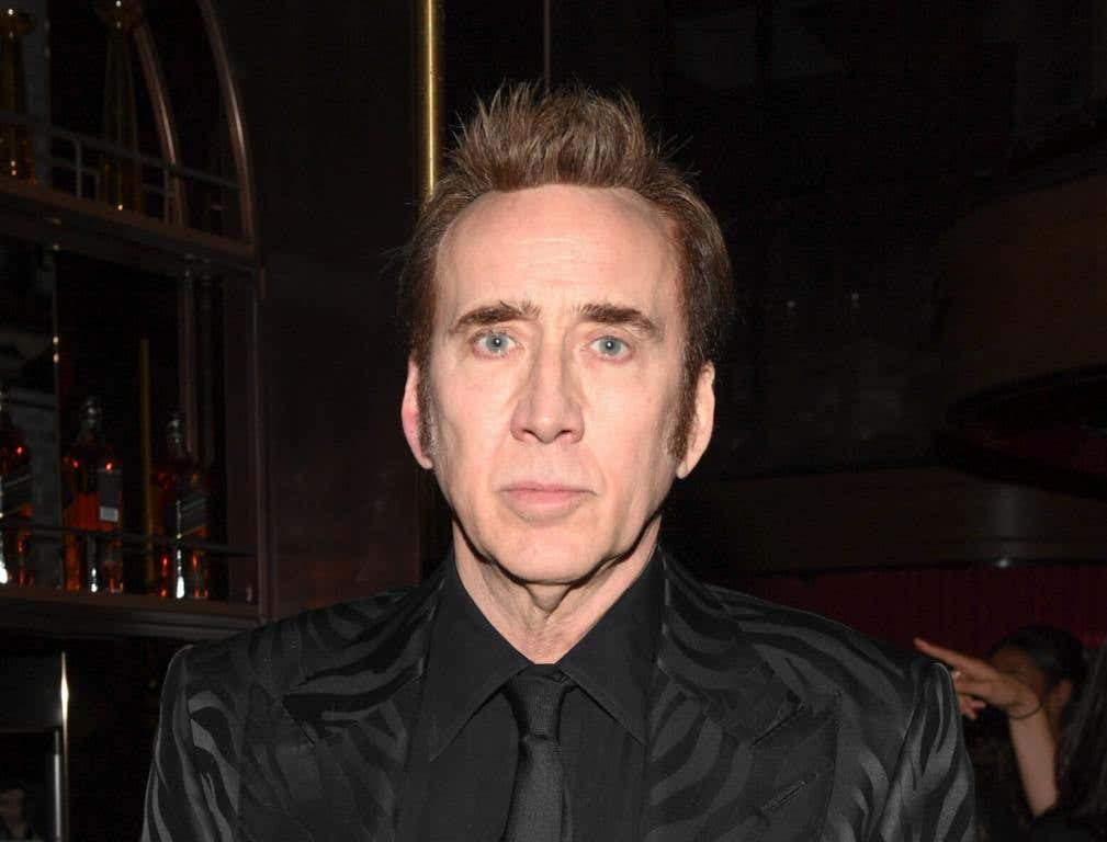 Nicolas Cage attends the "Dream Scenario" world premiere party looking straight ahead wearing a black dress shirt and tie with a leather jacket.