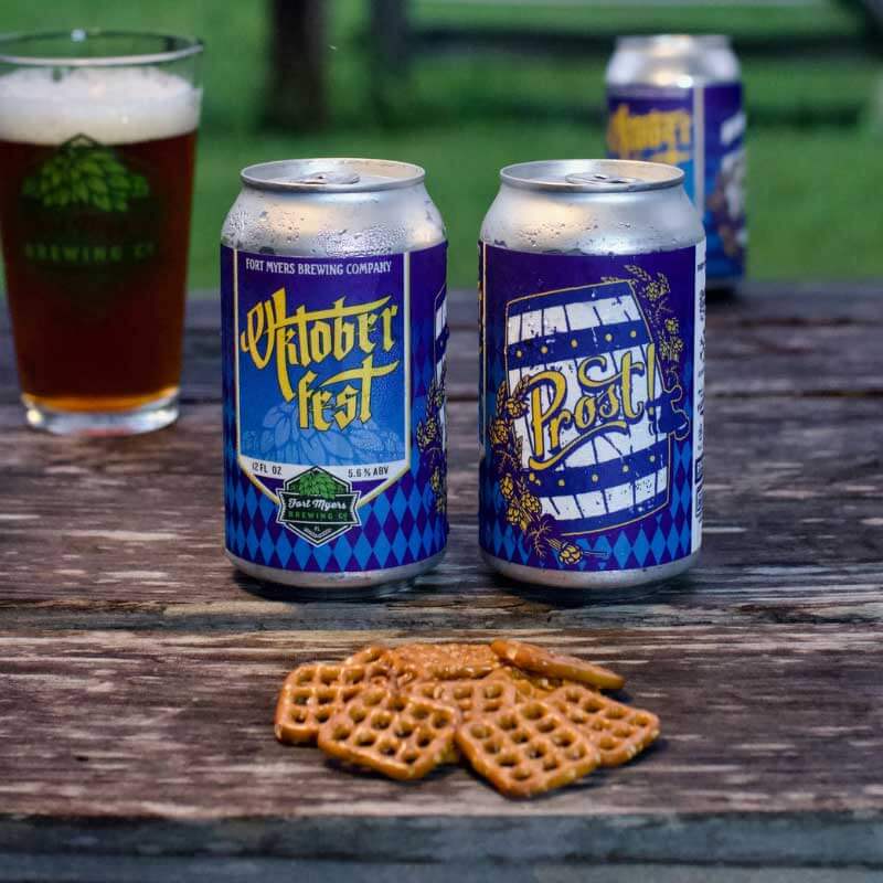 Two cans of beer, two glasses of beer and a stack of pretzels on a table outdoors for things to do this weekend