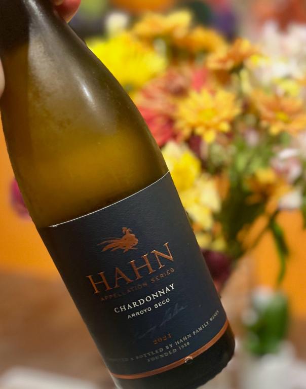 Bottle of Hahn Arroyo Seco Chardonnay with flowers in the background for aromatic white wines for Thanksgiving