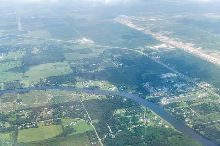 High angle aerial view of Ft Myers countryside landscape with farm fields Caloosahatchee river and clouds southwest in Florida Saharan dust plume air layer causing haze pollution and allergies