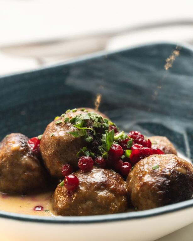 Numerous Swedish Meatballs on a plate garnished with green herbs and red berries at the New Swedish Restaurant In Naples