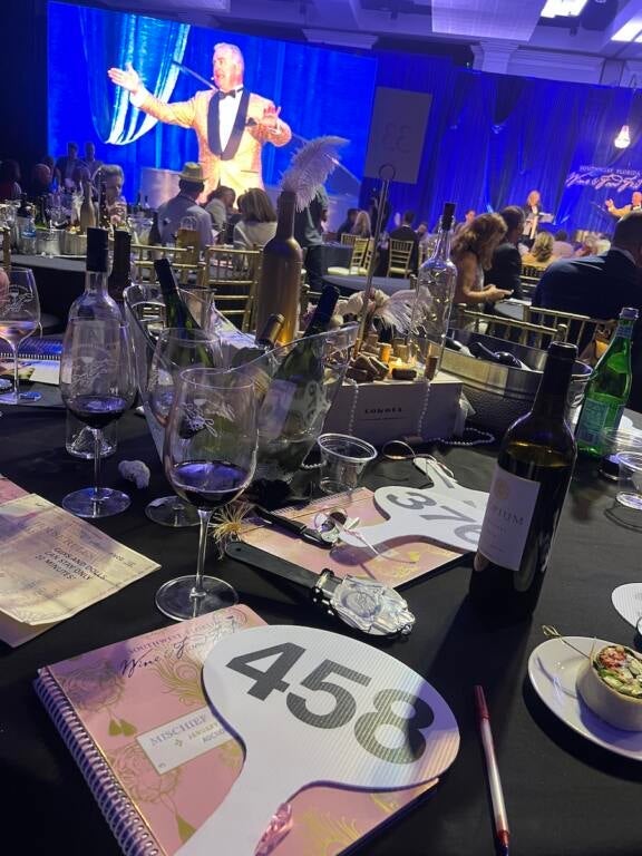 Table with a an auction paddle and number in foreground, stage and auctioneer in background