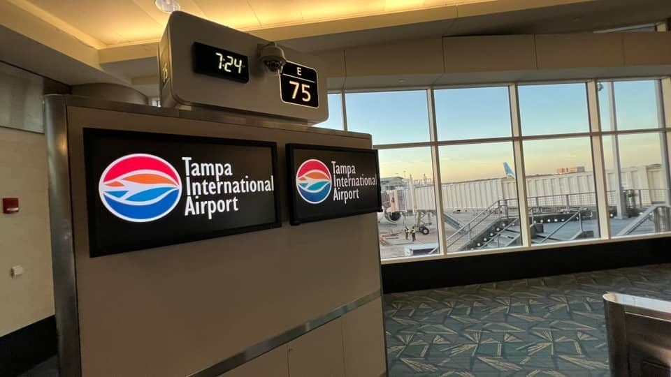 A sign reading Tampa International Airport in the airport terminal with a view of planes at the gate as Florida airports rank most stress free for travel