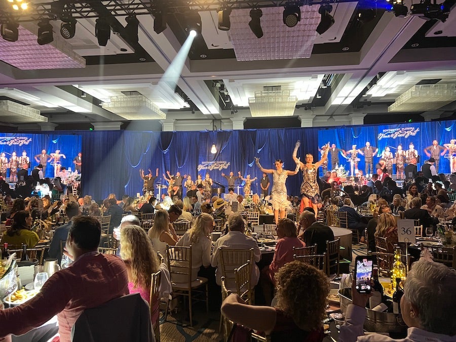 Ballroom full of people with their arms up at the SWFL Wine And Food Fest