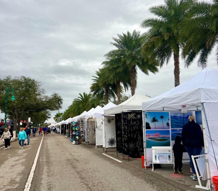 Row of tents lined up on a street, inside is artwork for Weekend Activities In SWFL