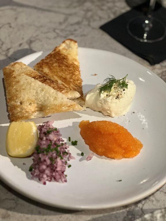 plate of orange Caviar, chopped onions, mound of cream and toast points