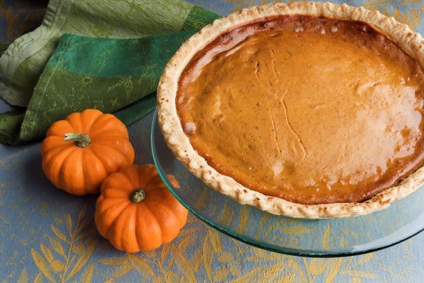 Whole pumpkin pie with two miniature pumpkins for 5 Comforting Pumpkin Spice Recipes For Fall