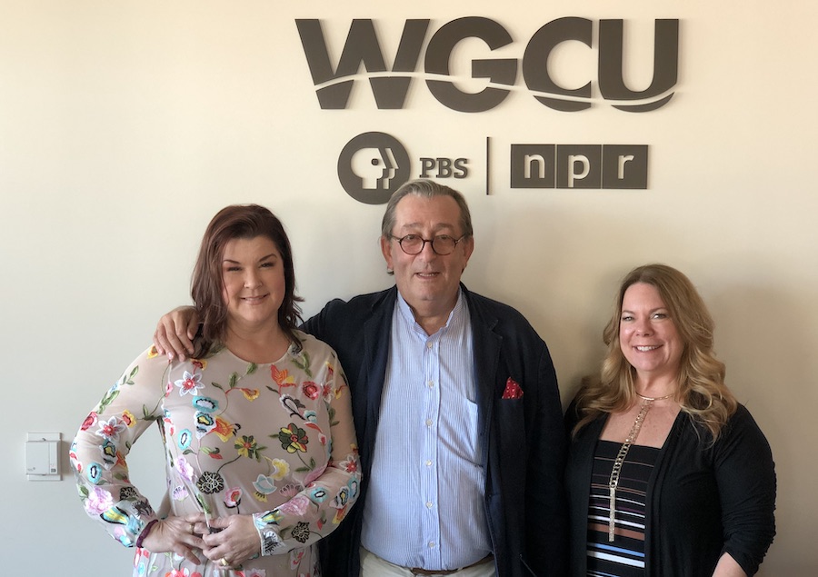 two girls and a man smiling, standing under a signe reading WGCU