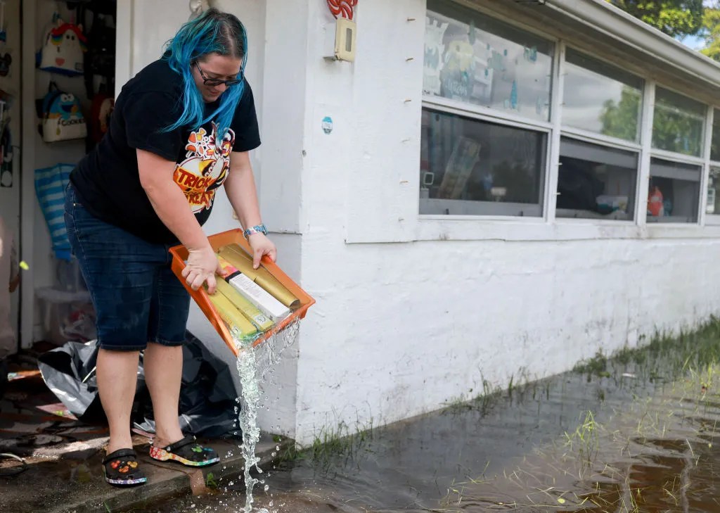 Hope Diterlizzi dumps flood water from a storage container as she cleans up after her home was inundated with water when Hurricane Milton passed through the area on October 10, 2024, in Punta Gorda, Florida. The storm made landfall as a Category 3 hurricane in the Siesta Key area of Florida, causing damage and flooding throughout Central Florida.