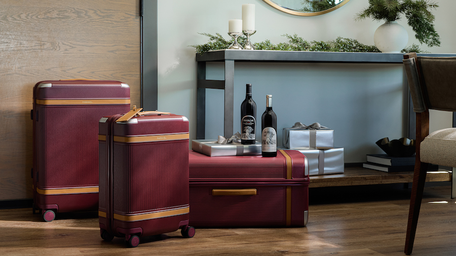 Three different sized suitcases on the floor with bottles of Silver Oak Wine