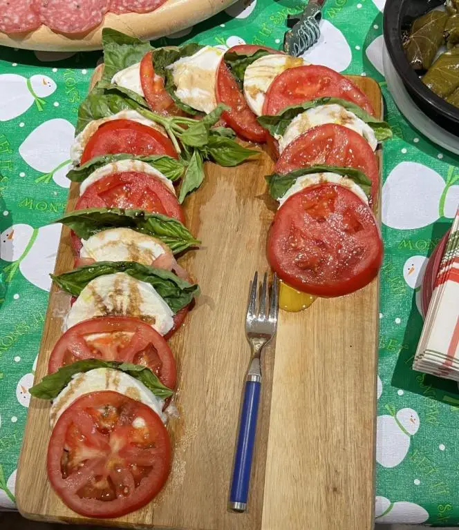 easy Christmas appetizers, tomato slices, mozzarella slices and basil leaves, layered and shaped to form a candy cane